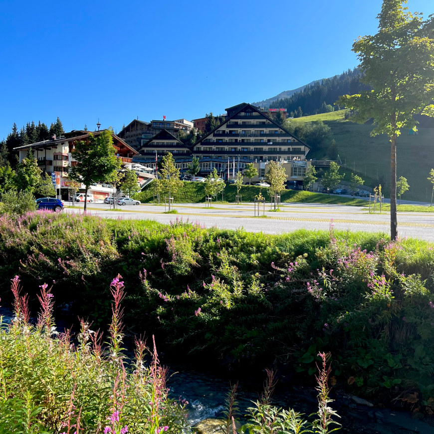 Der große Parkplatz von Hochfügen im Zillertal. Im HIntergrund die Hotels, im Vordergrund der Fluss. 