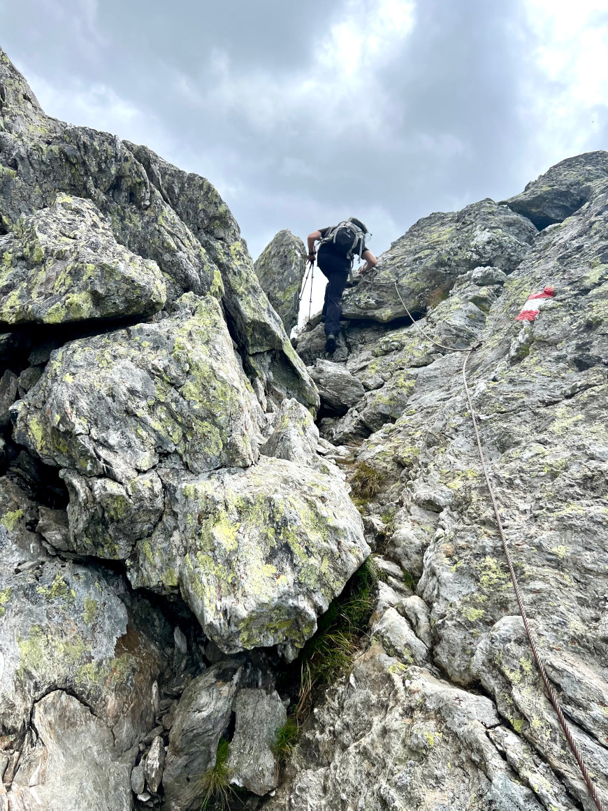 Eine Passage mit Seilversicherung: im Vordergrund das herabhängende Seil und die Steilen Felsen, im HIntergrund Thomas von tourtricks, der die Seilpassage fast überwunden hat. 