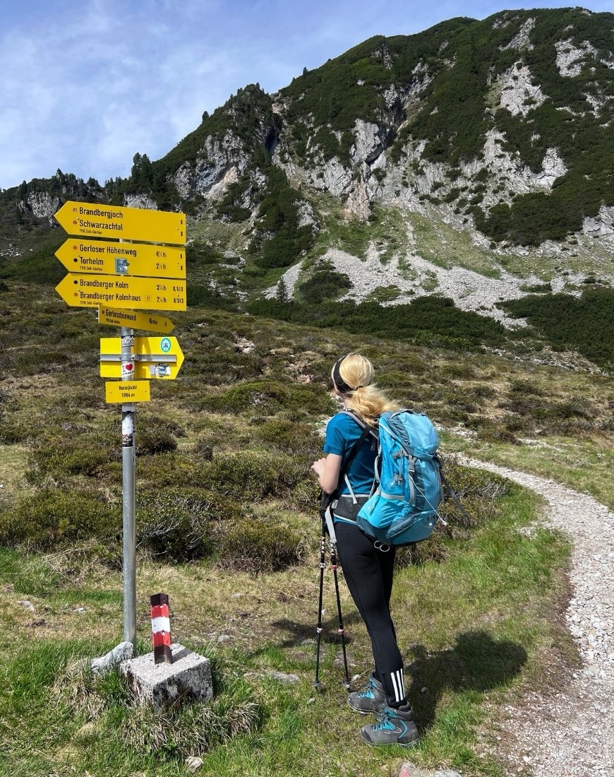 Wegweiser am Heimjöchl auf dem Weg zum Freikopf, davor steht eine Frau