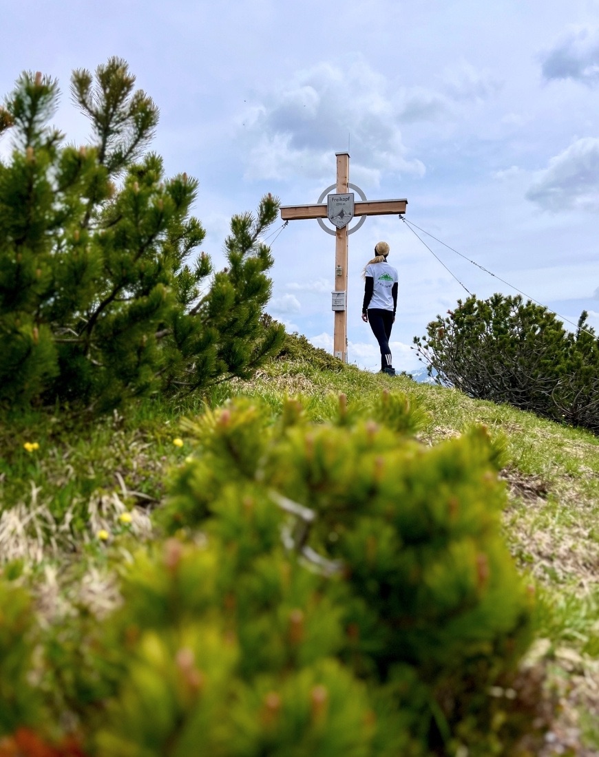Gipfelkreuz auf dem Freikopf mit weiblicher Person, die der Kamera mit den Rücken zugewandt ist.
