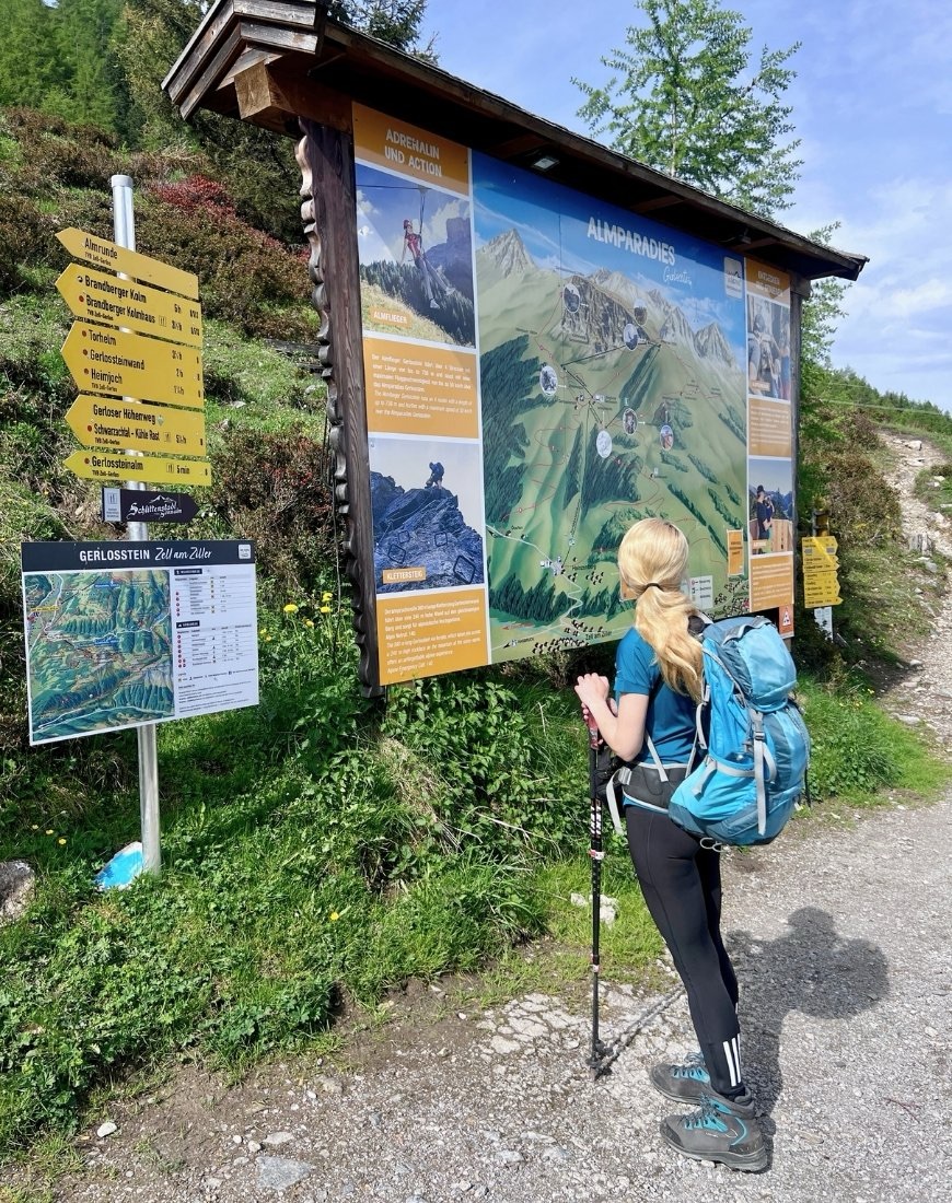 Schild mit geografischer Karte an der Bergstation der Gerlossteinwand. Davor steht eine Frau, die draufschaut.